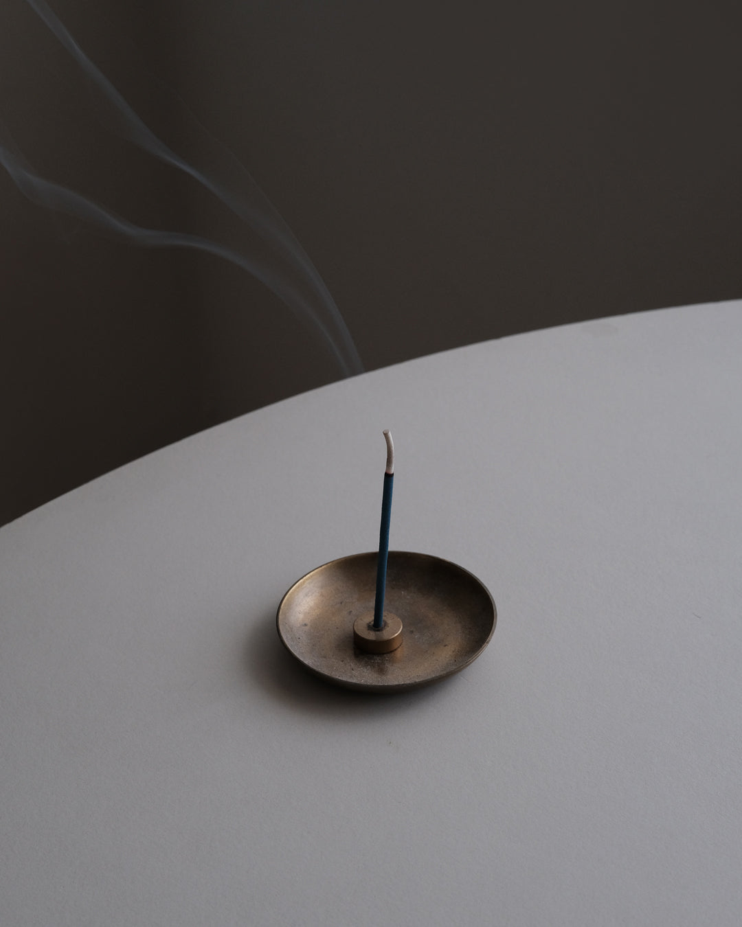 A singular incense burning on a rounded edge table
